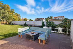 Fenced backyard featuring a patio area and a fire pit with custom bench