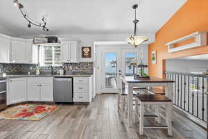 Kitchen with white cabinetry, granite counter tops,  tile wood-look flooring, backsplash, and stainless steel appliances