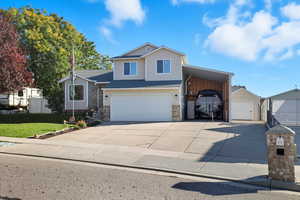 View of front of home featuring garage, tall carport, rv parking and shed