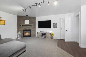 Living area featuring a stone fireplace, carpet flooring, and track lighting