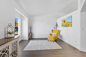 Sitting room with dark wood-style flooring and vaulted ceiling