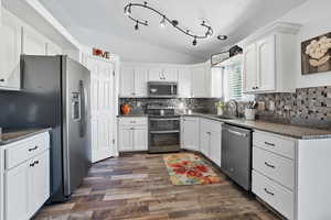 Kitchen with vaulted ceiling, stainless steel appliances, white cabinets, granite countertops