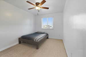 Bedroom with light colored carpet and a ceiling fan