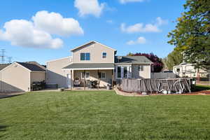 Rear view of property with a patio, a yard, an outdoor pool