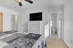 Primary Bedroom with ornamental molding, a ceiling fan, light colored carpet, light tile patterned flooring, and ensuite bath