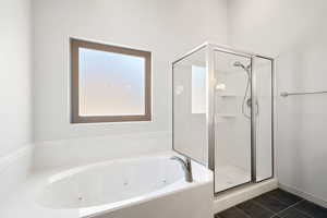 Full bathroom featuring a shower stall, a whirlpool tub, and dark tile patterned floors