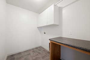 Laundry room with hookup for a washing machine, a desk, and cabinet space