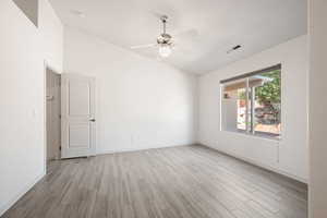 Empty room featuring light wood-style floors, ceiling fan, and high vaulted ceiling