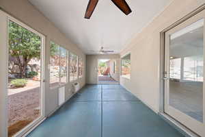 Unfurnished sunroom featuring a ceiling fan and concrete flooring