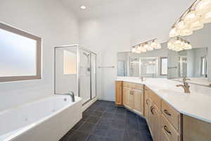 Full bathroom with a tub with jets, dark tile patterned flooring, a shower stall, double vanity, and recessed lighting