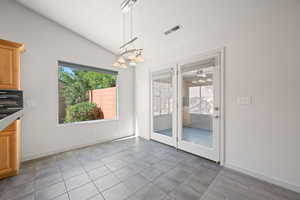 Unfurnished dining area featuring lofted ceiling, plenty of natural light, a chandelier, and a textured ceiling