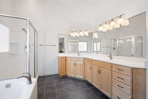 Bathroom featuring dark tile patterned floors, a stall shower, double vanity, and a bath