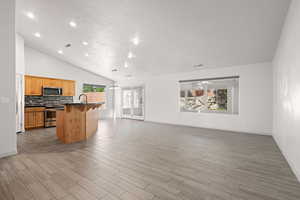 Kitchen featuring backsplash, dark countertops, a breakfast bar area, open floor plan, and hanging light fixtures