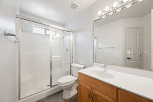 Bathroom featuring a shower stall, vanity, and dark tile patterned floors