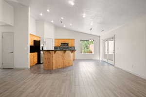 Kitchen with a kitchen bar, wood tiled floors, a textured ceiling, appliances with stainless steel finishes, and a center island with sink