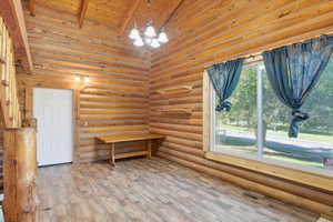 Unfurnished room featuring a chandelier, wood ceiling, wood finished floors, and rustic walls