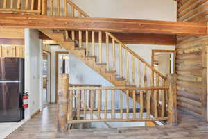 Stairs featuring wood finished floors and log walls