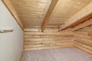 Bonus room with a wooden ceiling with exposed beams, light colored carpet, and log walls
