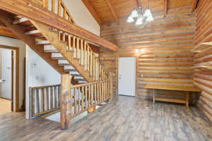 Entryway featuring high vaulted ceiling, wood finished floors, a wood ceiling with exposed beams, stairs, and a chandelier