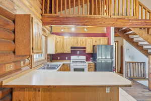 Kitchen featuring light countertops, white range with gas cooktop, freestanding refrigerator, track lighting, and a peninsula