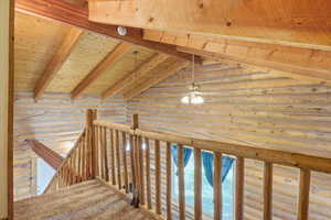 Staircase with wooden ceiling, a ceiling fan, and log walls