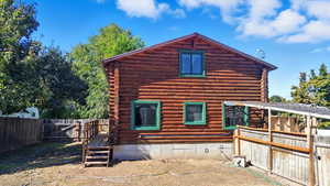 Back of property with log exterior, a fenced backyard, and a deck