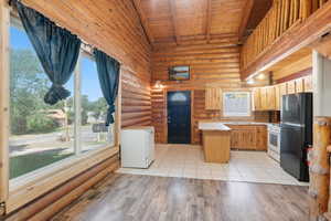 Kitchen featuring white appliances, rustic walls, a wood ceiling with exposed beams, high vaulted ceiling, and light wood-style flooring