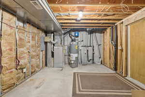 Unfinished below grade area with water heater, heating unit, and electric panel