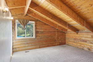 Bonus room featuring log walls, wood ceiling, and carpet flooring