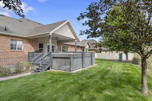 Rear view of property featuring brick siding, a shingled roof, and a hot tub