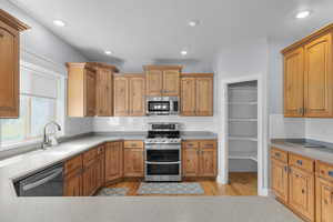 Kitchen with stainless steel appliances, backsplash, recessed lighting, brown cabinets, and light wood-style flooring