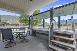 View of patio featuring a hot tub, a mountain view, and outdoor dining space