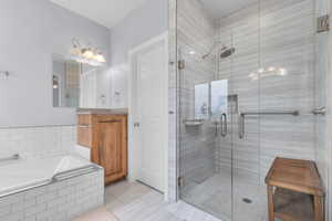 Full bathroom with a shower stall, a garden tub, vanity, and light tile patterned floors