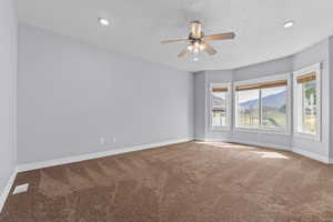 Empty room featuring a mountain view, carpet, ceiling fan, and recessed lighting