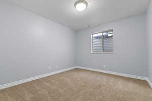 Carpeted empty room featuring baseboards and a textured ceiling
