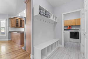 Mudroom with separate washer and dryer, light wood-style flooring, and recessed lighting