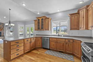 Kitchen featuring brown cabinets, glass insert cabinets, appliances with stainless steel finishes, light wood finished floors, and recessed lighting