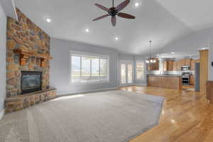 Unfurnished living room featuring recessed lighting, a fireplace, vaulted ceiling, a chandelier, and light wood-type flooring