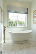 Bathroom with a wainscoted wall, tile walls, and a freestanding tub