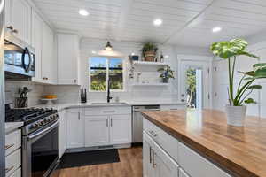 Kitchen featuring appliances with stainless steel finishes, white cabinetry, butcher block countertops, recessed lighting, and a wooden ceiling with exposed beams