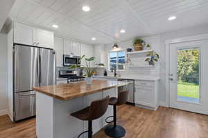 Kitchen featuring wooden counters, stainless steel appliances, white cabinets, light wood-style flooring, and recessed lighting