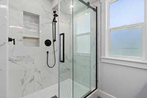 Bathroom with a marble finish shower and healthy amount of natural light