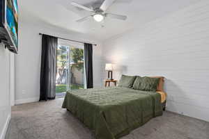 Bedroom featuring carpet floors, ceiling fan, and wood walls