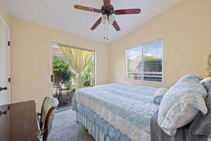 Carpeted bedroom featuring multiple windows, access to outside, lofted ceiling, and ceiling fan