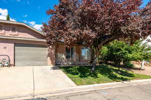 View of front of home featuring a front lawn, concrete driveway, stucco siding, and a garage