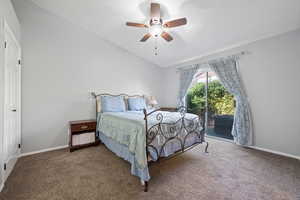 Bedroom featuring vaulted ceiling, carpet flooring, access to outside, and a ceiling fan