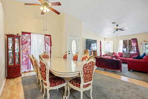 Dining area with ceiling fan, light wood-style flooring, and high vaulted ceiling