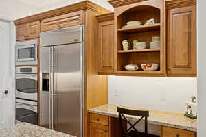 Kitchen featuring solid wood cabinets and floors, pot filler, open shelving, granite countertops, decorative backsplash, and crown molding,