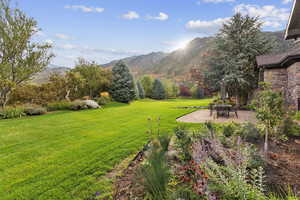 View of grassy yard featuring a patio and a mountain view