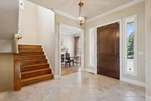 Entryway with crown molding, stairway, and light tile patterned floors